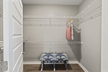 A walk in closet with a and a rack with clothes